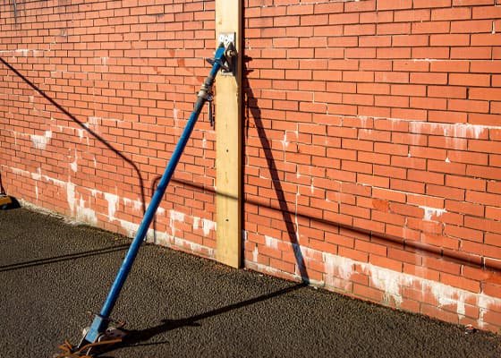 Apuntalamiento metálico diagonal con madera colocado en un muro